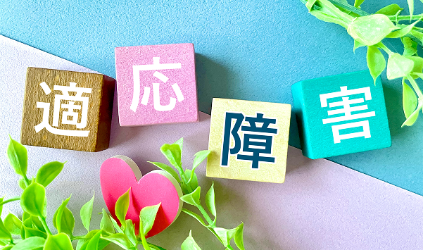 「適応障害」と書かれたカラフルな積み木のブロックと植物の装飾