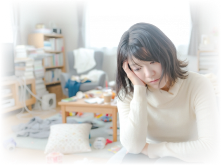 散らかった部屋の中で頬杖をつき、落ち込んだ様子で座っている女性